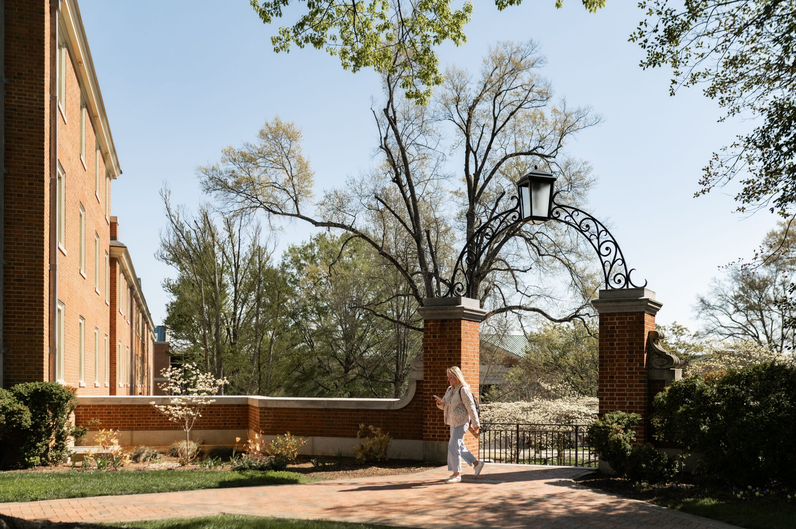student walking through brick campus gateway scaled