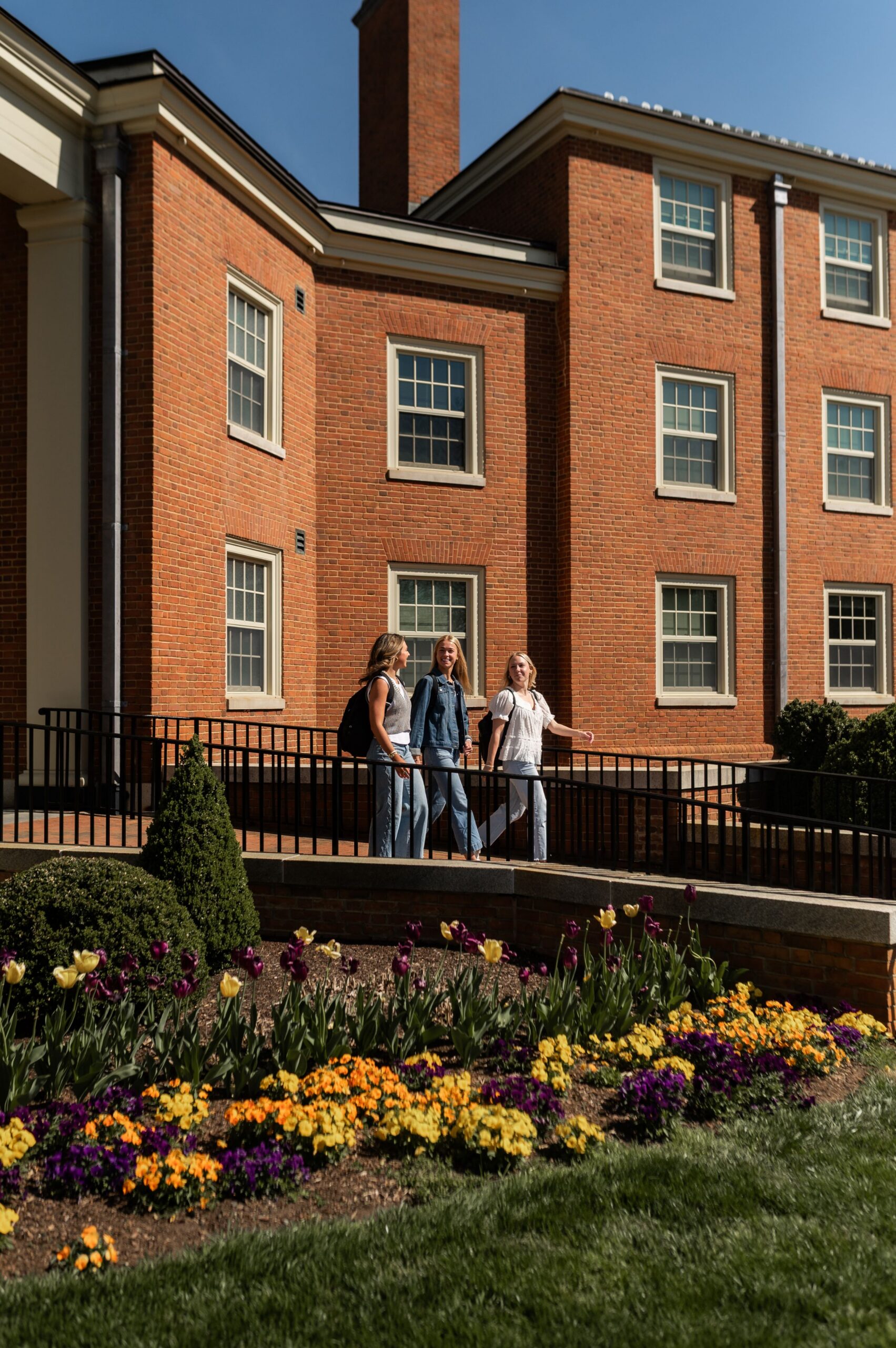 undergraduates strolling past brick academic hall scaled